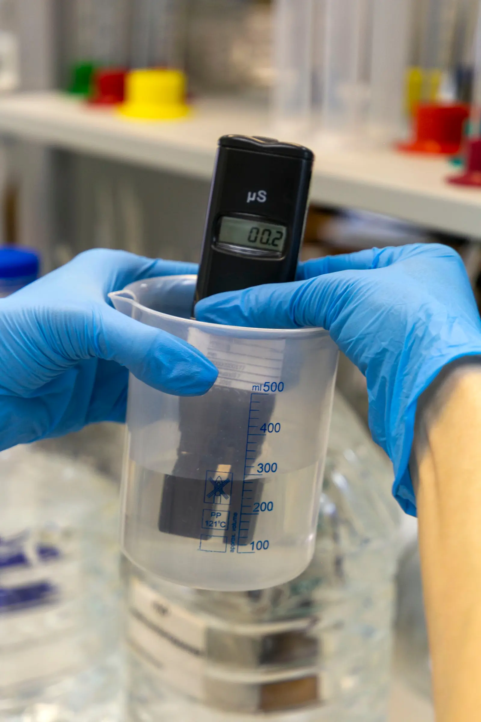 Gloved hands holding a meter in a water sample